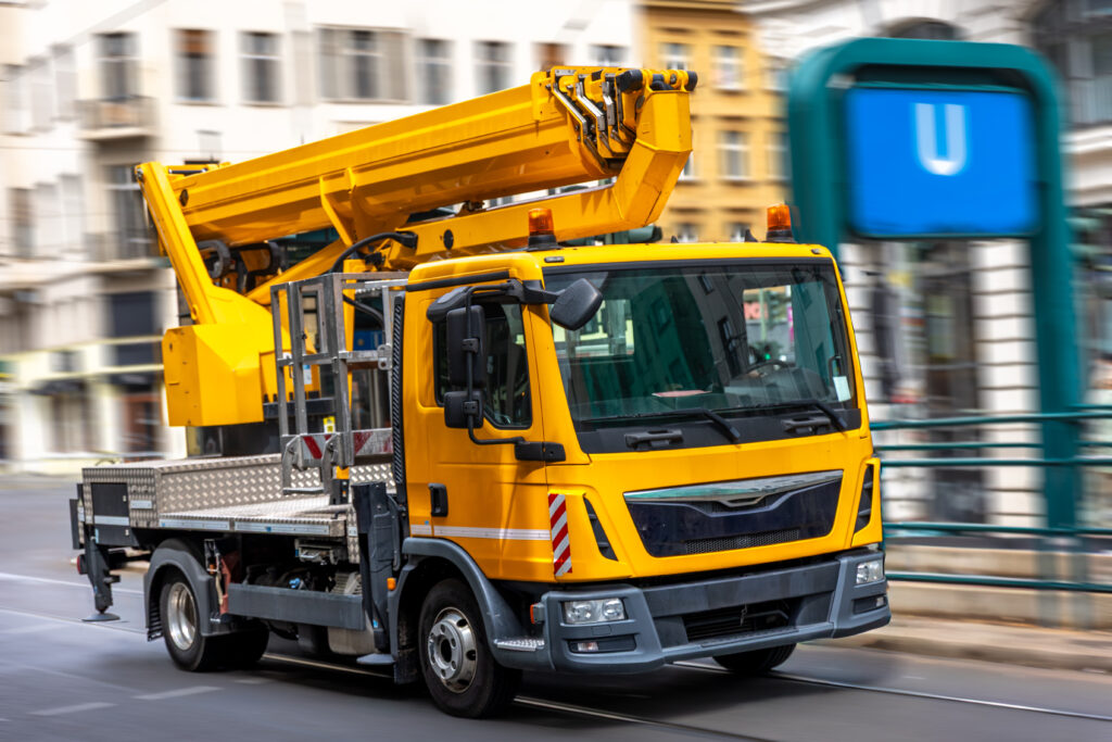 Żółta ciężarówka serwisowa z podnośnikiem hydraulicznym