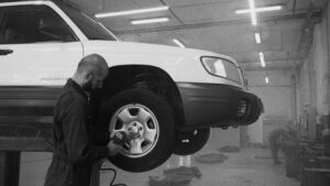 Monochromatyczny obraz mechanika używającego klucza udaru na kole samochodu w warsztacie naprawczym